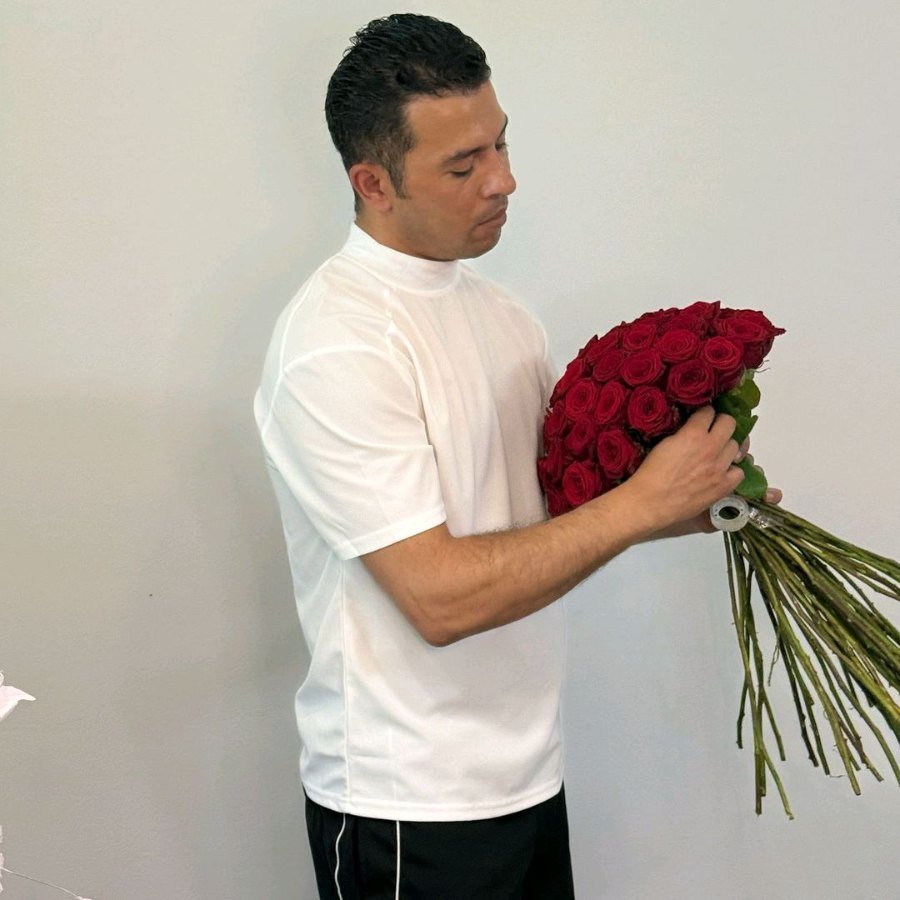Alaa Alabedallah mit einem Strauß roter Rosen im Atelier von Lotus Blumen